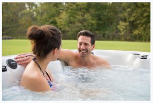 Couple in a hot tub with grass behind them